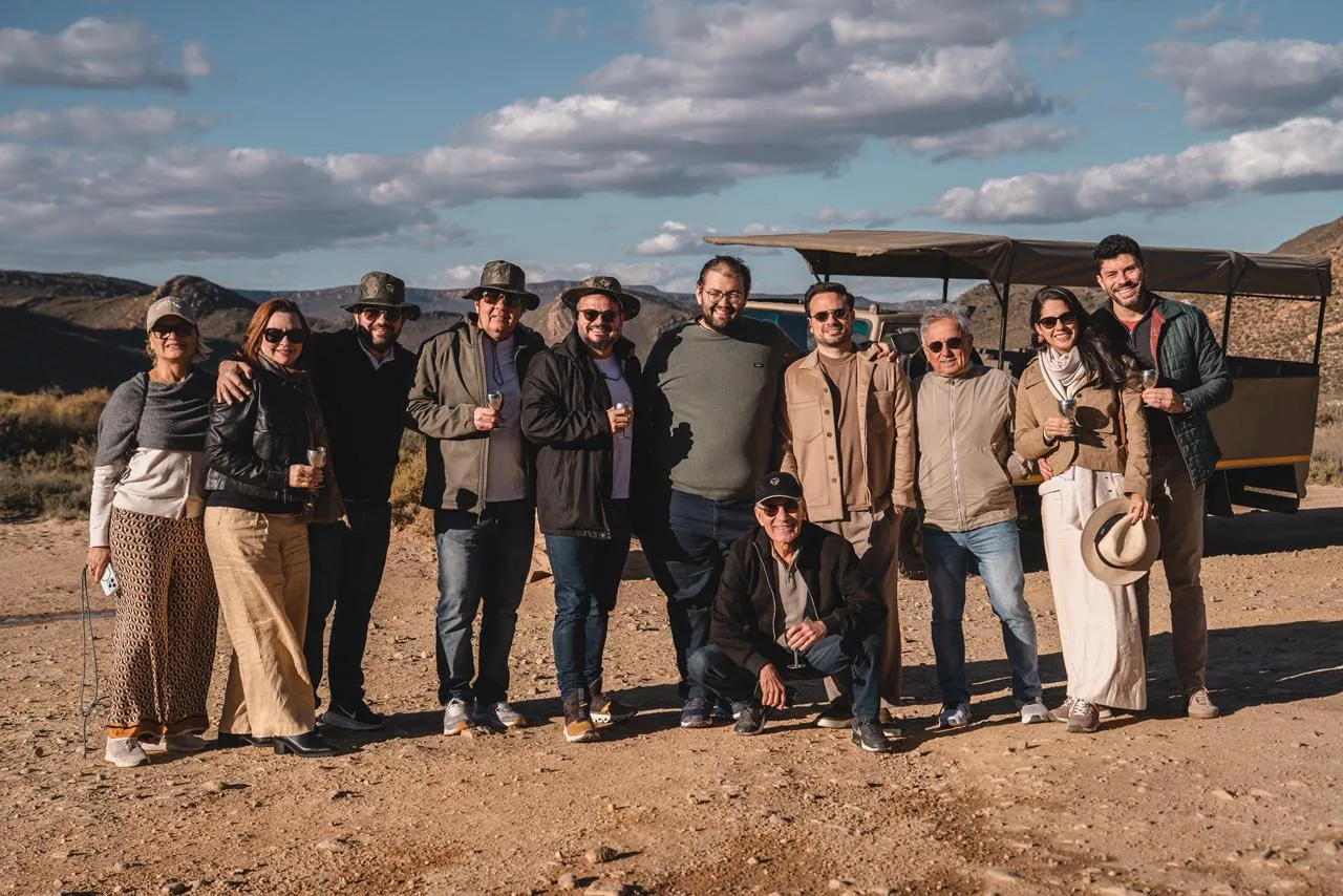 O grupo reunido junto ao veículo de safári, diante das montanhas.