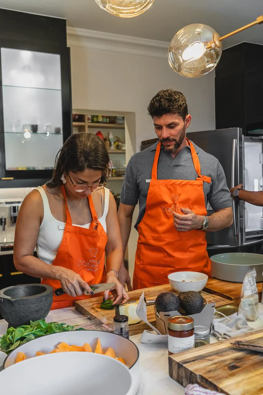 Participante de avental cozinha junto à bancada.