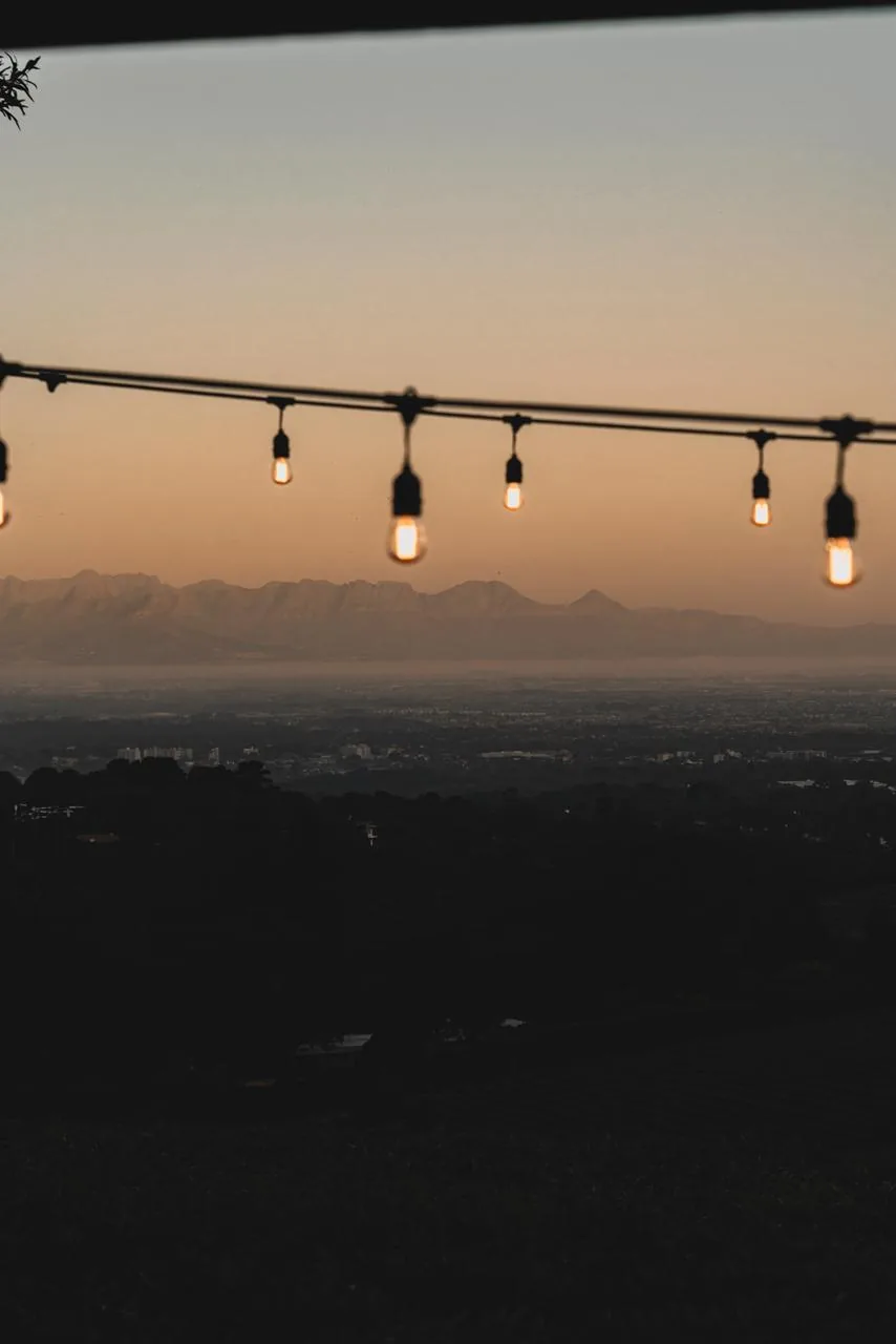 Luzes suspensas diante da paisagem de Beau Constantia ao entardecer.