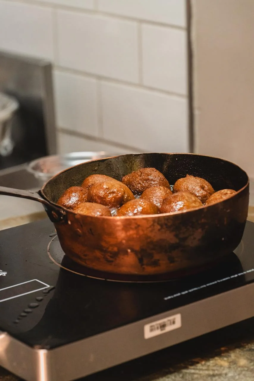 Pequenas porções de massa fritam numa panela.