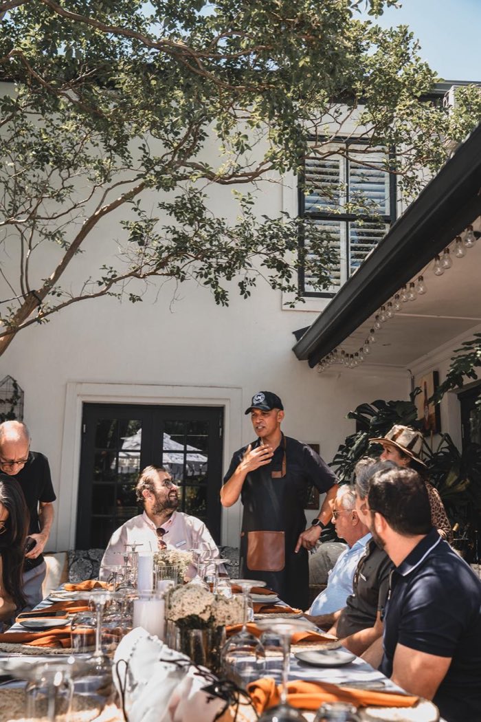 Reuben Riffel conversa com os convidados à mesa de sua casa